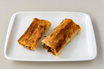 Turkish style meat stuffed filo dough borek served kol boregi. Cheese and minced pie are sliced on a marble background. Turkish name: Kol Boregi, ispanakli, kiymali, Su Boregi