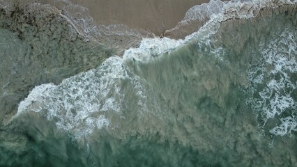 Aerial view of Ocean waves crashing onto a sandy shoreline