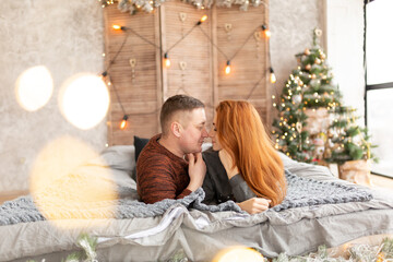 Obraz na płótnie Canvas portrait of a couple on the bed near the New Year tree. the winter vacation. Christmas morning family celebrations