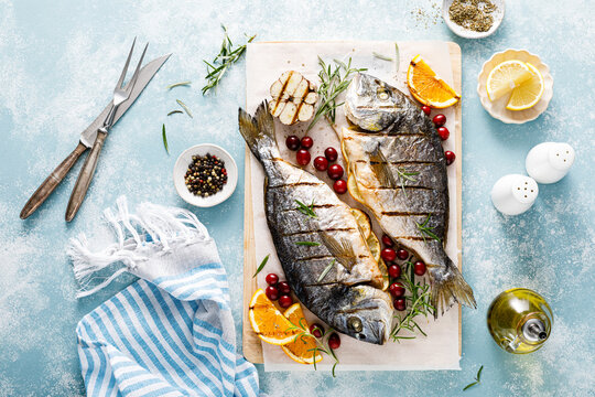 Dorado fish grilled with oranges, cranberries and rosemary, Mediterranean food. Christmas festive healthy dinner, top view