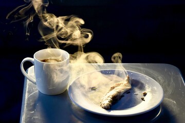 Closeup of a plate with freshly cooked food, a cup of coffee with steam rising from the cup