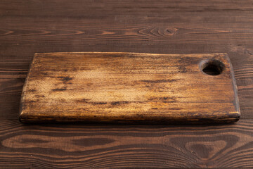 Empty rectangular wooden cutting board on brown wooden. Side view
