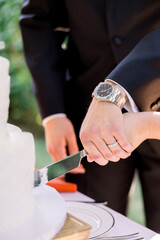 Fototapeta premium Bride and groom have their hands together on a knife and are cutting their wedding cake