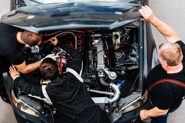 mechanics check the car engine before driving. under the hood. extreme sport. racing car engine problems.  - obrazy, fototapety, plakaty