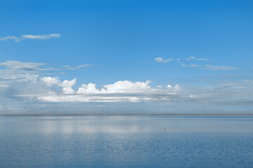 Beautiful white blue clouds over lake, symmetric sky background, cloudscape on lake Ik, Russia. Nature abstract, cloudy sky reflected on water, calm windless weather, natural environment
