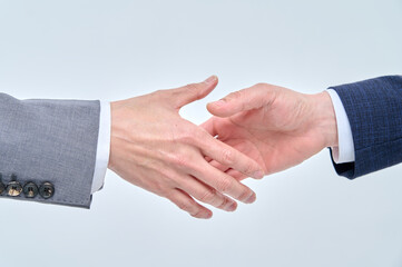 Two men in suits are shaking hands.