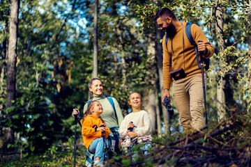 Smiling family of four exploring nature while hiking in forest.