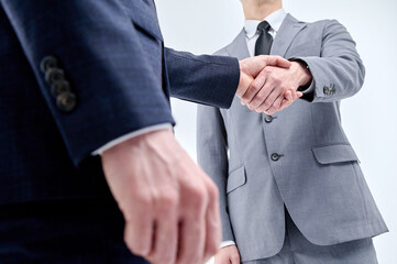 Two men in suits are shaking hands.