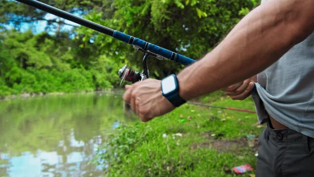 young guy with a fishing rod in his hands, twists a reel and fishes in a river in a rainforest.