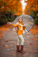 teenage girl with a transparent umbrella in her hands on a walk in the autumn on a city street