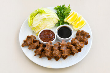 Cig kofte (raw meatball) with lettuce, tomato, pickle and lemon, hot Chee kofta. Turkish local raw food concept.Table scene of assorted take out or delivery foods. Doritoslu duble cig kofte durum.