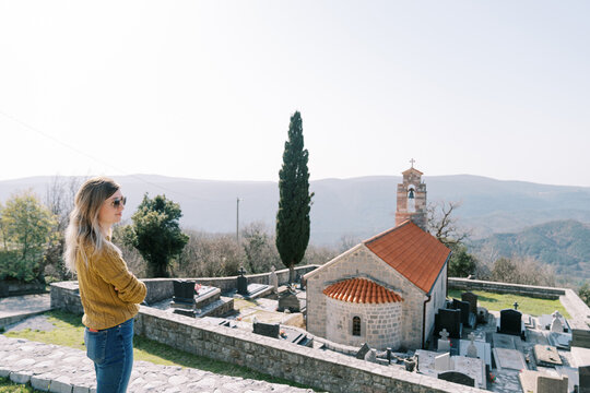 Young woman stands on an observation deck near the Church of St. Nicholas. Baosici, Montenegro