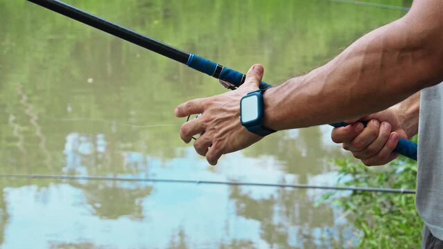 young guy with a fishing rod in his hands, twists a reel and fishes in a river in a rainforest.