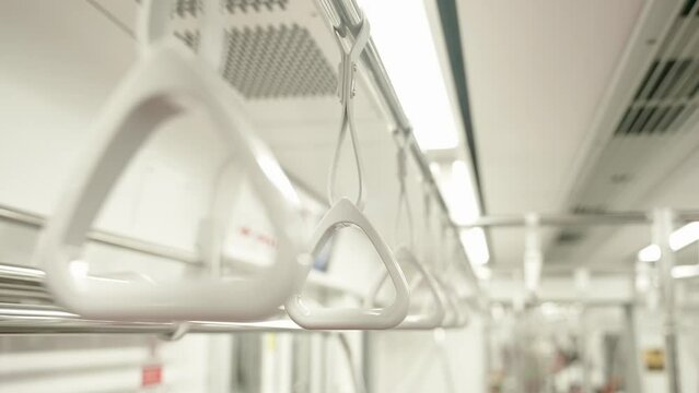 Close up of row hanging handrails inside the empty metro train during the pandemic. Passenger safety in public city transport