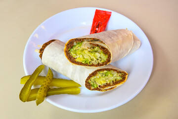 Cig kofte (raw meatball) with lettuce, tomato, pickle and lemon, hot Chee kofta. Turkish local raw food concept.Table scene of assorted take out or delivery foods. Doritoslu cig kofte durum.
