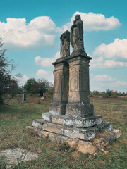 Fototapeta premium Ancient stone statues in an abandoned cemetery. Headless statue. Old cemetery.