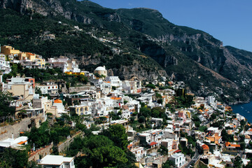 Amalfi Sea Coast with Umbrellas, people swim, and Yachts. Clean and blue sea where to swim. Photo for tourism and summer background. Concept of vacation and beach life in the open air  