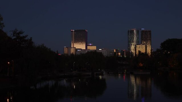 Autumn evening in Bucharest 4k video pan camera. Beautiful night view with the skyscraper modern office buildings from the North of Bucharest, Baneasa and Pipera areas landscape over Floreasca Lake.