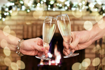 Toasting the New Year in front of a fire in a fireplace with glasses of champagne