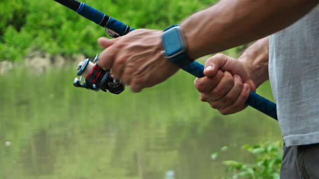 young guy with a fishing rod in his hands, twists a reel and fishes in a river in a rainforest.