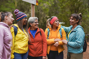 Group of multi generational women having fun during hiking day in the forest - Multiracial female community doing trekking sport activity - obrazy, fototapety, plakaty