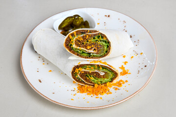 Cig kofte (raw meatball) with lettuce, tomato, pickle and lemon, hot Chee kofta. Turkish local raw food concept.Table scene of assorted take out or delivery foods. Doritoslu duble cig kofte durum.