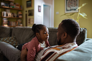 Little girl looking at father on the couch at home
