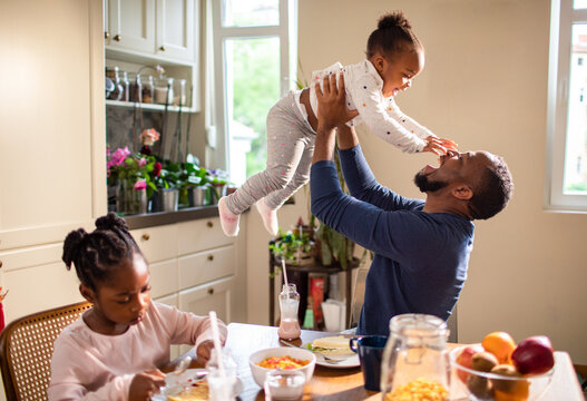 Single father having breakfast with his two young daughters at home