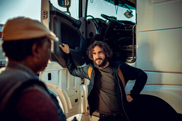 Young truck driver talking to colleague about to hit the road together