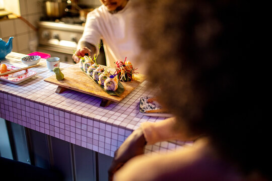 Chef presenting sushi to a customer in restaurant