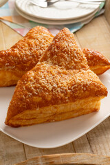 Plate with baked sweet puff apple triangles pastry as a snack close up 