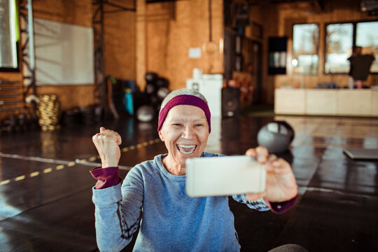 Senior woman holding smartphone in gym - Powered by Adobe