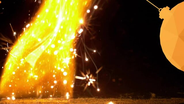 Animation of hanging bauble over fireworks and fire against black background