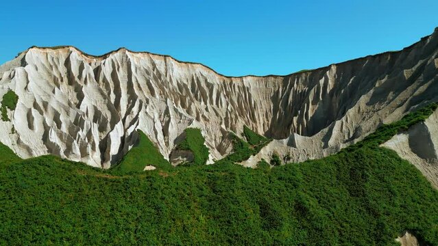 Beautiful aerial of the white cliffs on the south coast of England. Clip. Green summer forested hills and blue sky.