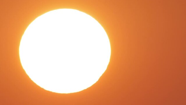 A big sun rising filmed with a telephoto lens. This sunrise could symbolize global warming or climate change.