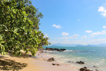 Sandy and rocky beach against the backdrop of the turquoise sea, tropical paradise, time for vacation and relaxation.