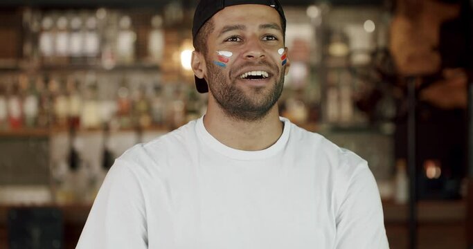 Portrait of hispanic man football fan with painted stripes on face cheering for favorite team at pub. Young male supporter watching soccer match, smile and celebrate goal at bar. 