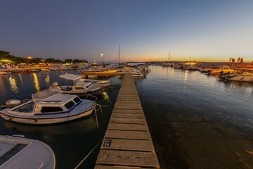 Obraz premium Sunset in the harbor of the Croatian coastal village of Fazana over a jetty for boats in summer evening