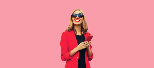 Beautiful elegant lady business woman with mobile phone wearing red blazer on pink studio background