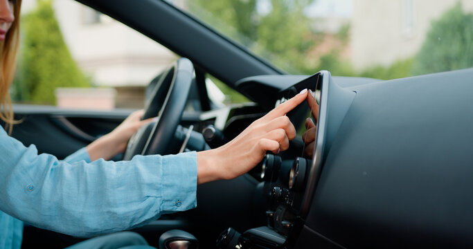 Side view of caucasian woman hand which typing needed coordinates on navigator touchscreen with modern assistance functions. Girl making scrolling and typing text on touch screen monitor on car.