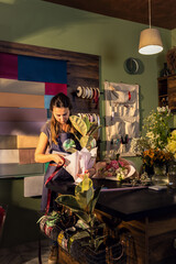 Young woman working in her flower shop decorate house plants for sale.