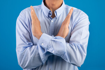 unrecognizable man making cross hands gesture over blue studio background