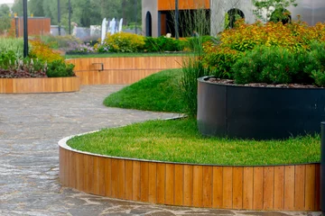 Foto auf Acrylglas A park with a beautiful landscape design with bends on flower beds, after the rain. © KseniaJoyg