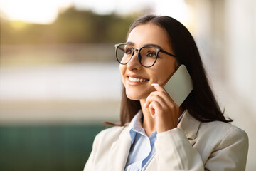 Smiling pretty millennial european lady in suit, glasses enjoy work conversation, call by phone