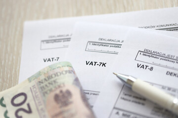 Declaration for tax on goods and services VAT-8, VAT-7K, VAT-7 form on accountant table with pen and polish zloty money bills close up