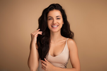 Happy brunette woman touching her beautiful long hair - Powered by Adobe