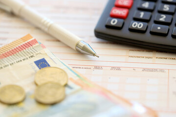 Filling italian tax form process with pen, calculator and euro money bills close up. Tax paying...