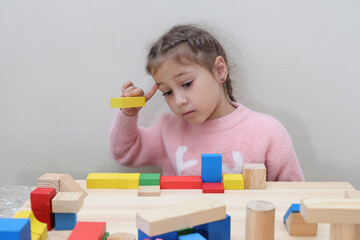 Caucasian preschool girl playing at a table with wooden cubes
