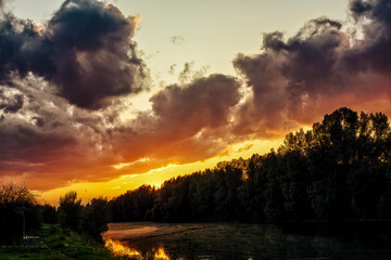 A beautiful sunset over the river with a fisherman in a boat in the early morning.