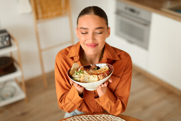 Woman holding bowl of salad in a bright kitchen